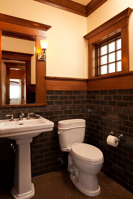 Powder room wainscot in dark glazed subway tile with relief border