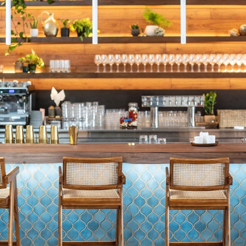 Restaurant bar front in turquoise ogee tile with cane-back bar stools