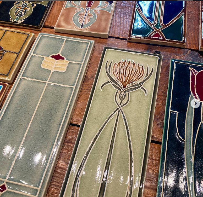 Arts & Crafts relief tiles in assorted glazes, with a thistle tile at center